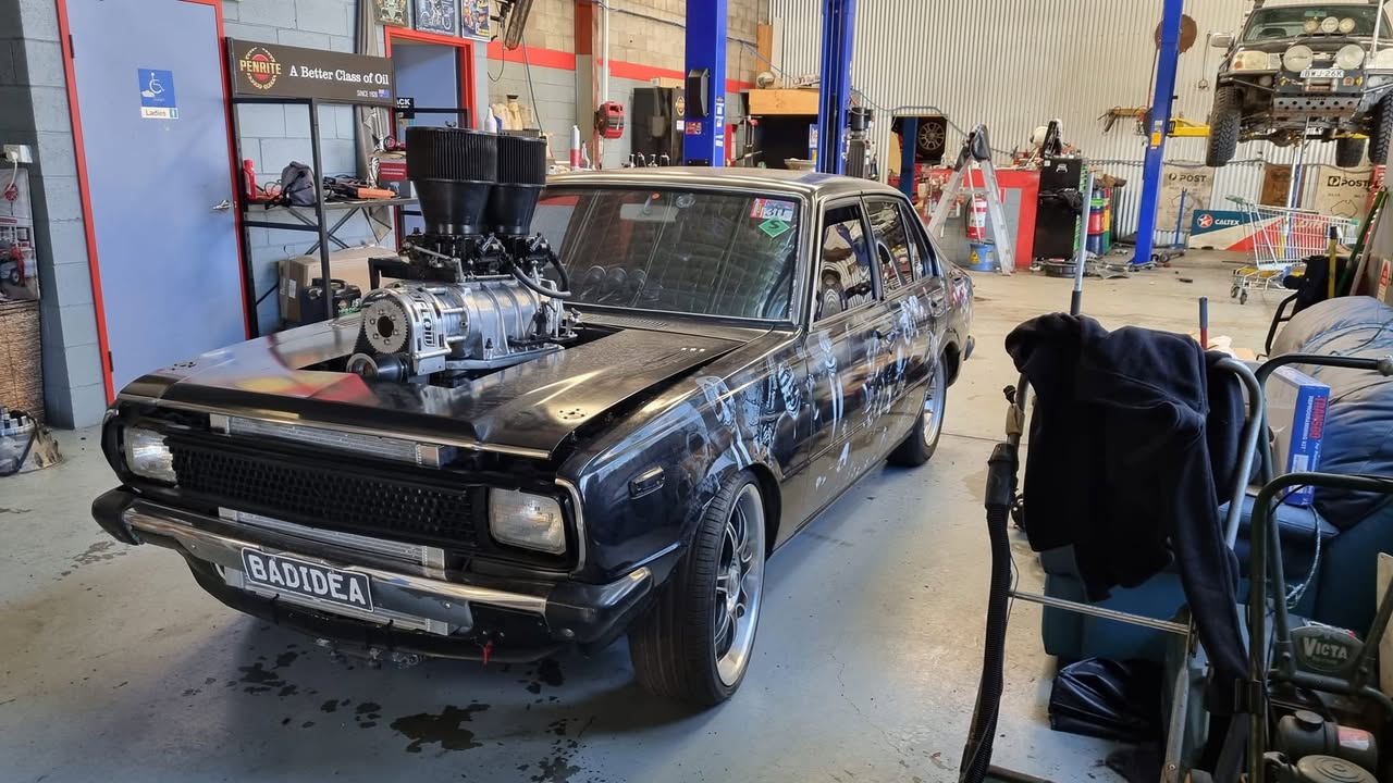 Inside the R & M workshop bay — supercharged Torana, oil signage, hoist